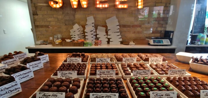 Sign that reads Sweet hangs in front of a counter full of chocolate truffles