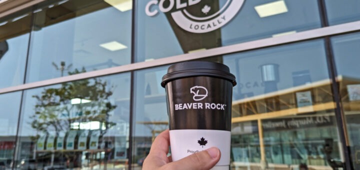 Hand holding up Beaver Rock coffee cup in front of the shop