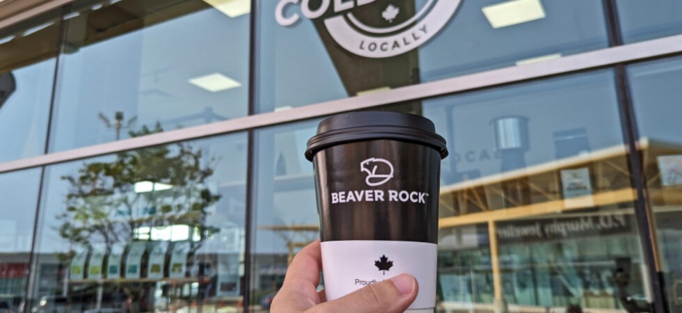 Hand holding up Beaver Rock coffee cup in front of the shop