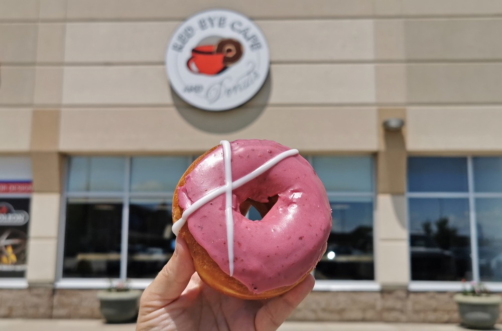 pink frosted donut in from of store called Red Eye Cafe