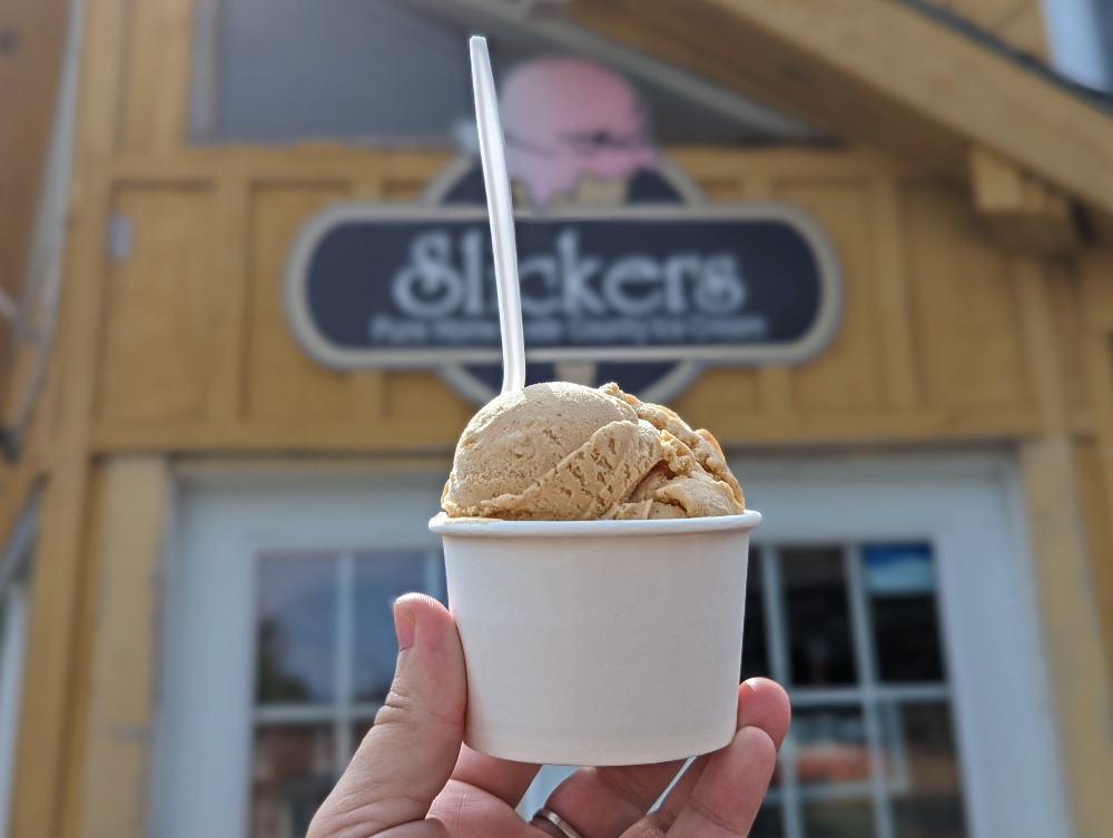 Hand holding up ice cream in a cup in front of Slickers in Bloomfield