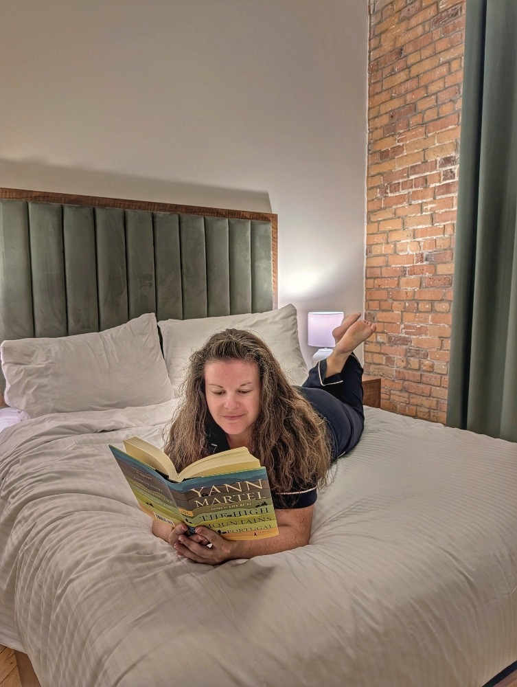 me laying on the bed at Tri Century Mill Suites reading