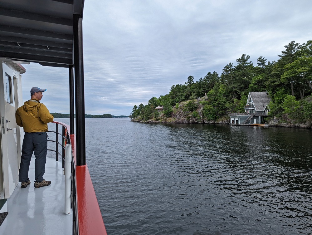 Man standing aboard Peerless II, looking out at views of Lake Rosseau, on one of the Sunset Cruises in Muskoka