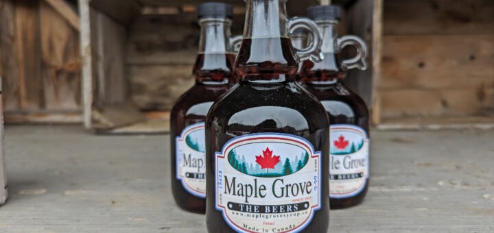Bottles of Maple Grove maple syrup lined up on a shelf