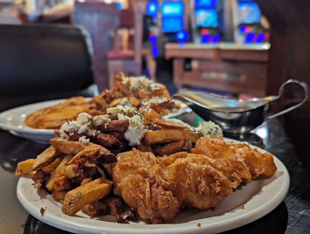 Plate with fish and chips as well as fries.