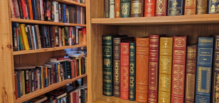 Close up of vintage books on a bookshelf with more bookshelves in the background