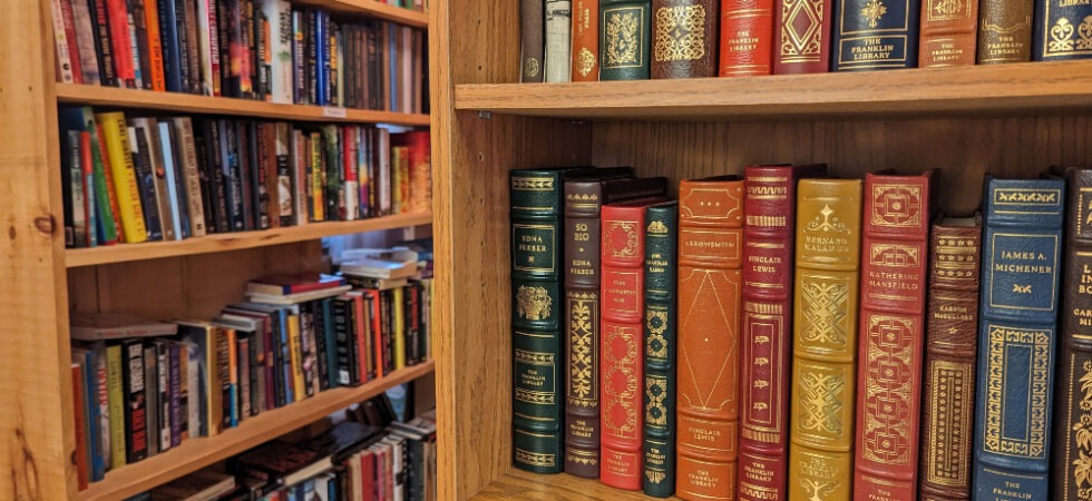 Close up of vintage books on a bookshelf with more bookshelves in the background