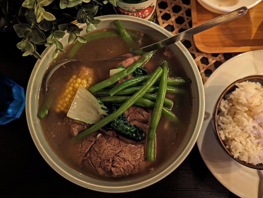 Bowl of beef soup with bowl of rice beside it