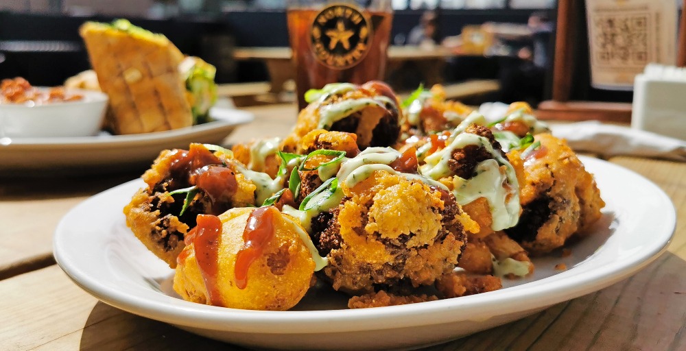 Plate of deep fried cauliflower bites with a glass of pop behind it