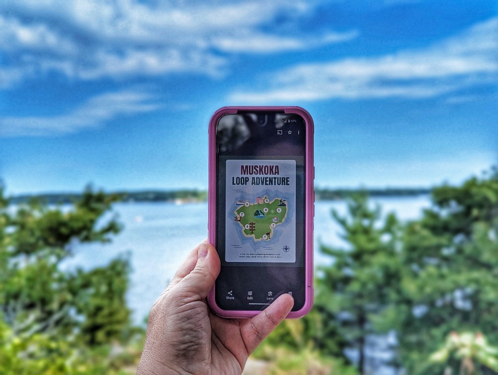 Hand holding up a cell phone with the first page of the Memorable Route Muskoka Loop Adventure itinerary