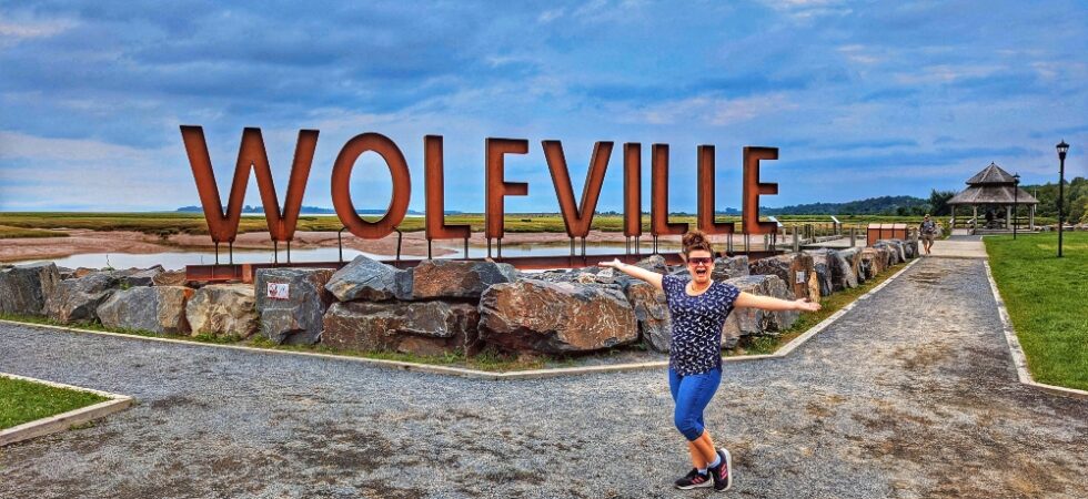 me standing in front of the Wolfville sign in Waterfront Park