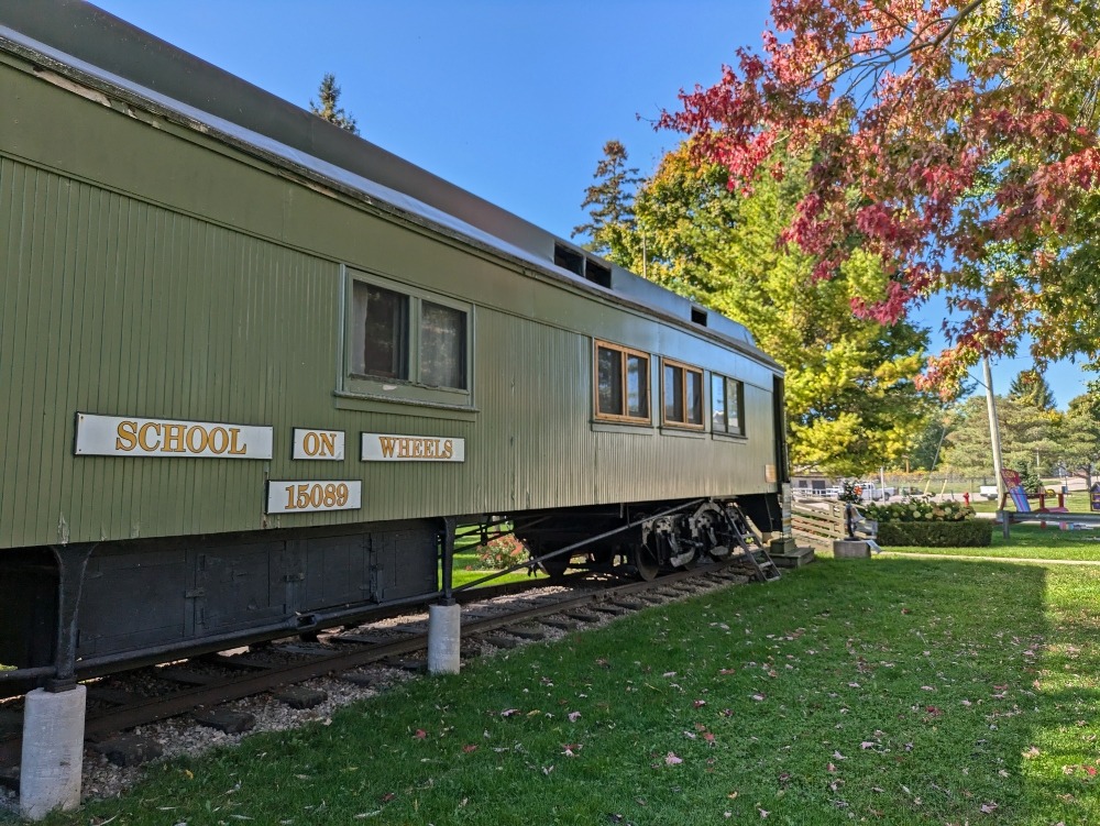 Exterior of railcar on tracks in a park. The railcar is the School on Wheels Museum