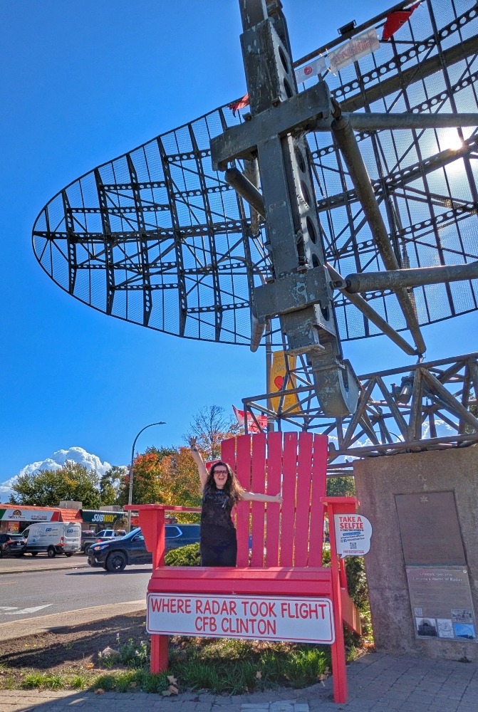 Me standing on a giant red chair in front of a large radar antenna in Clinton