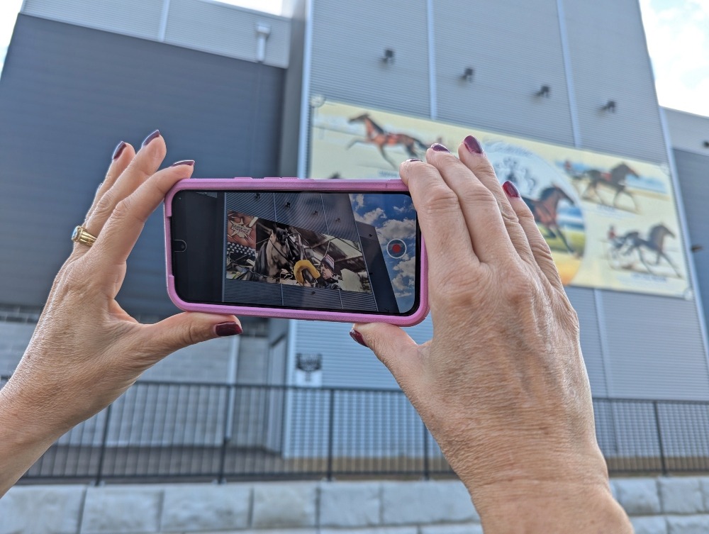 hands holding up a cell phone with animated horse mural in Clinton