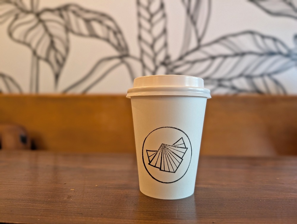 Coffee cup in from of mural inside Kit Coffee