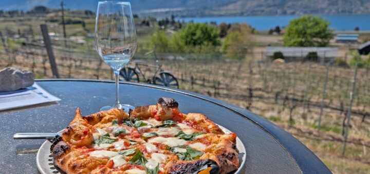 Pizza and glass of wine at Chain Reaction Winery in Penticton. The view is of the lake and mountains