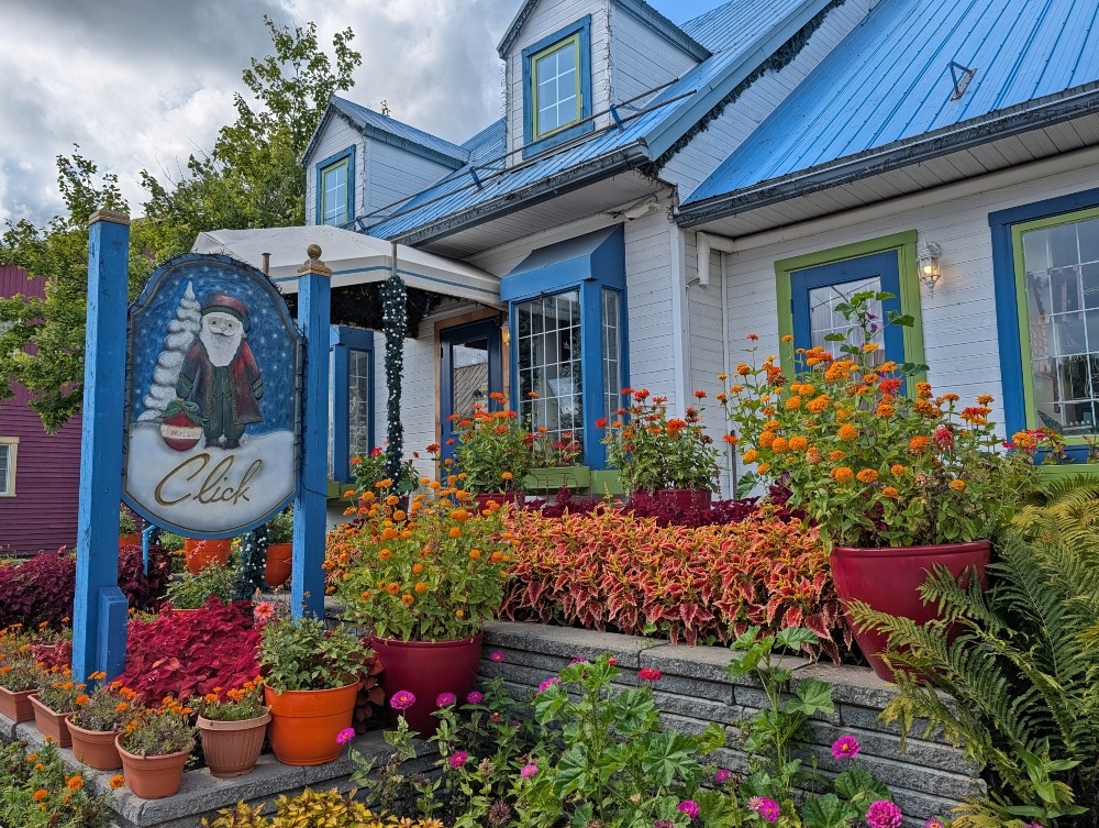 Blue and white building that is a Christmas shop, with plants and flowers out front