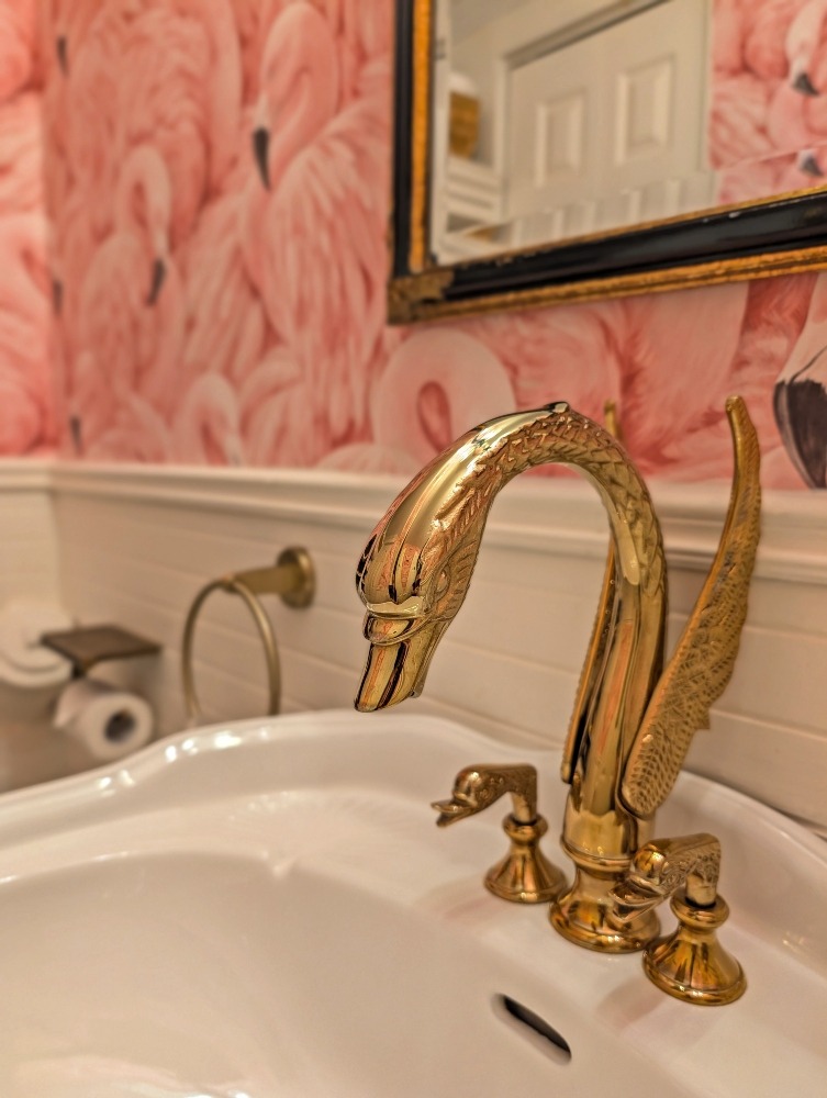 Powder room at The Old Mill Manor with flamingo wallpaper and a focus on the swan faucet