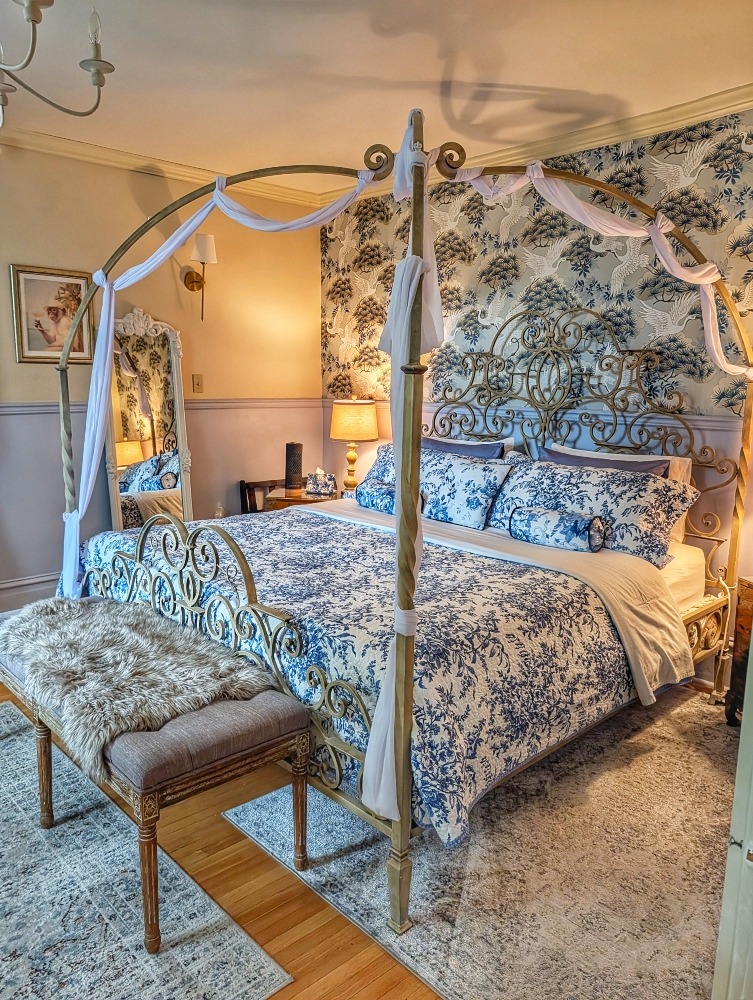 Ornate bed frame with blue toile bedding and similar wallpaper
