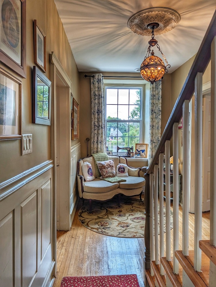 cozy nook at the Old Mill Manor, in the hallway, a small sofa sits below a window