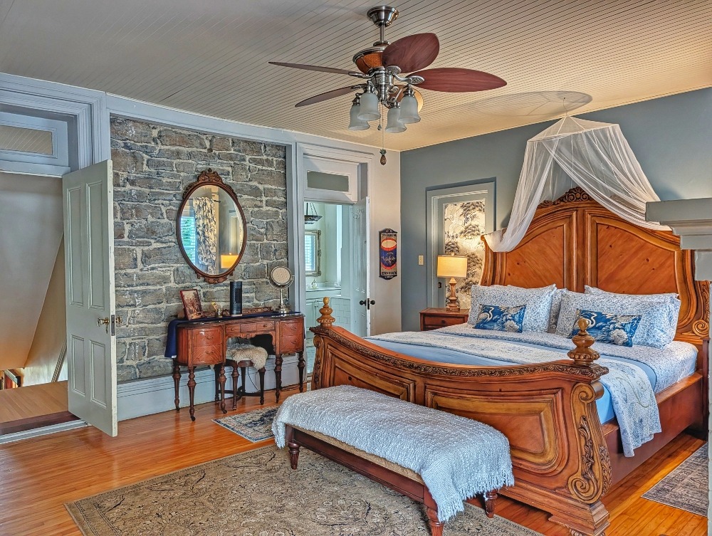 large room at the Old Mill Manor with a massive bed with dresser and fan