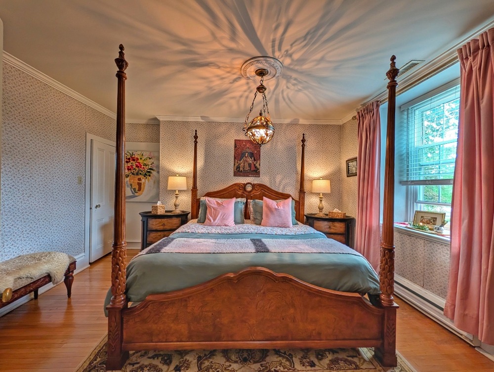 Four poster bed with pink drapes and ornate light fixture