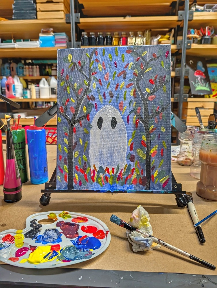 A painting of a ghost in the forest with paint supplies around it at The Craft Witch